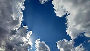 Wolken öffnen sich und geben ein Stück blauen Himmels frei.