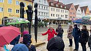 Die Lehrkräfte betrachten das „Ensemble Stehende als Dreiergruppe“ von Lothar Fischer auf dem Neumarkter Marktplatz.